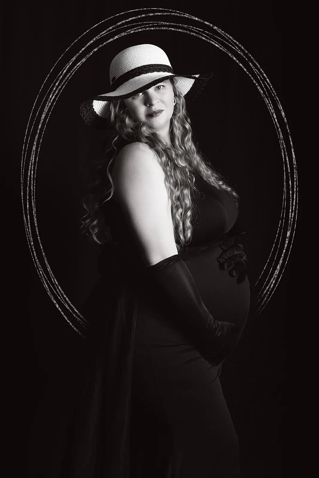 Nicole Marie Baker in black dress holding her belly and looking at the camera, Port St. Lucie maternity photography