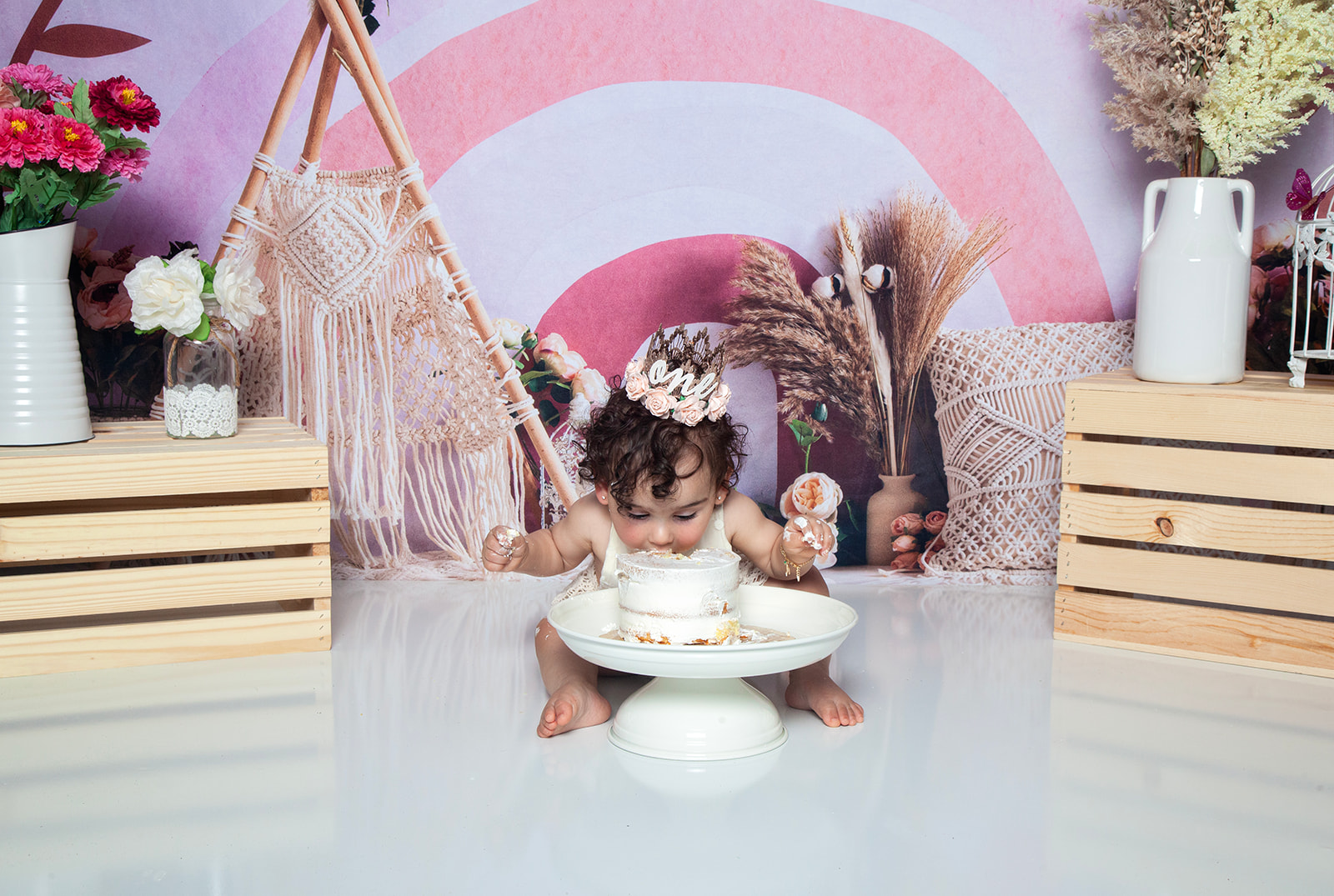 Baby smashing face into cake while wearing flower crown