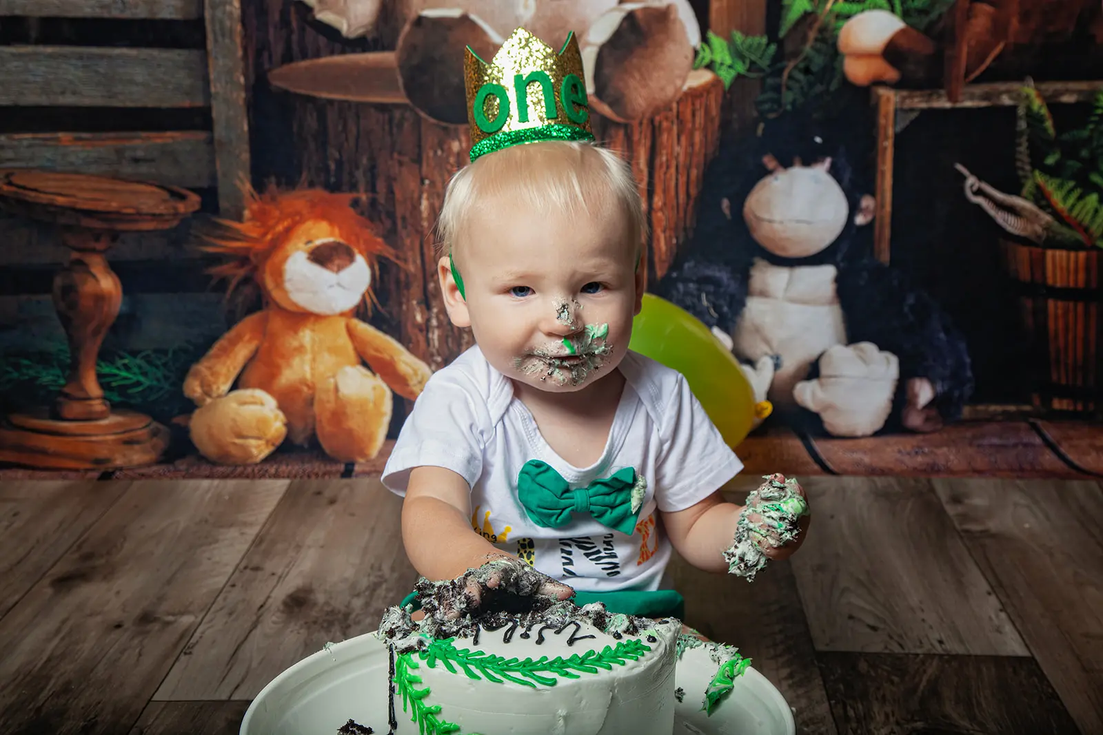 Baby with cake on hands and face looking at the camera, captured by Nicole Marie Photography, a photographer in Port St. Lucie