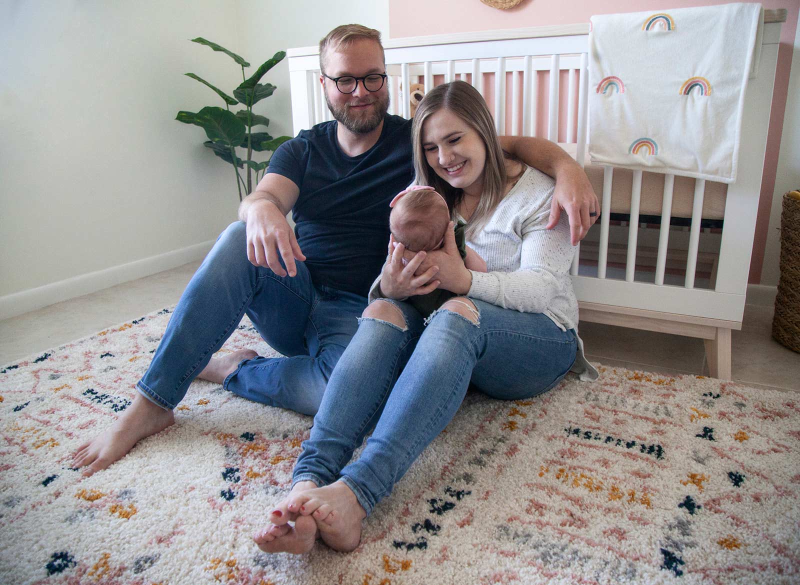 Married couple holding each other and smiling at their newborn baby