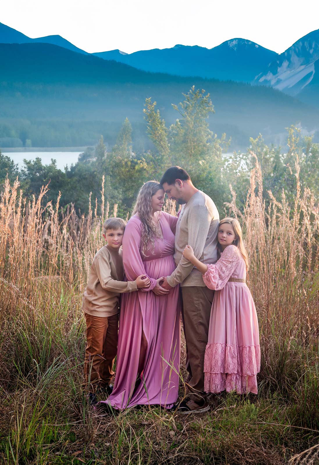 Man and pregnant wife with their two children in mountainous setting