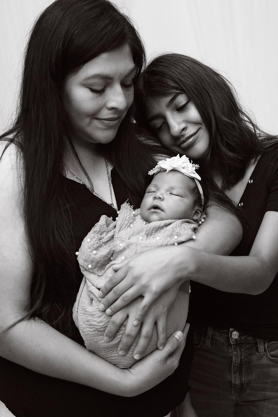 Two women holing a newborn baby and smiling at it